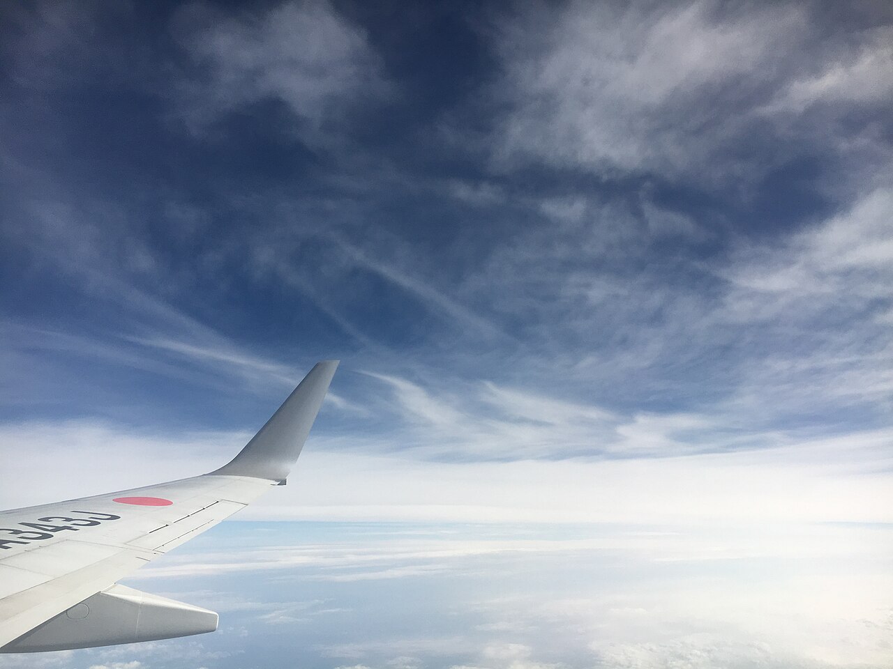 Aircraft wing above scattered clouds.